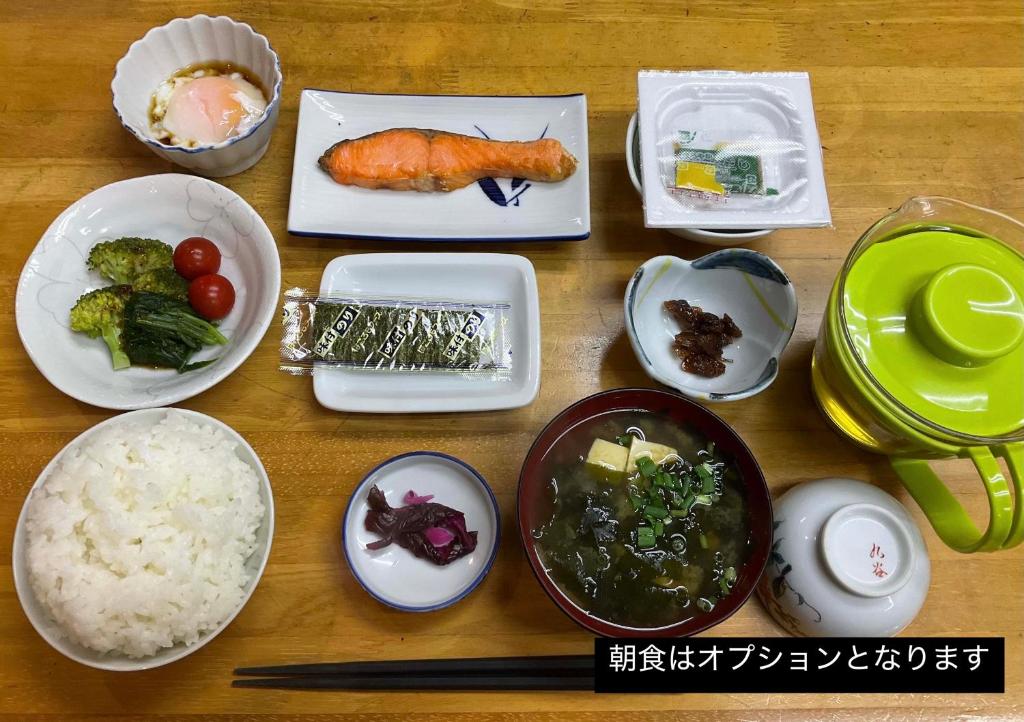 une table en bois avec des assiettes de nourriture dessus dans l'établissement Business Hotel Shizusato Ryokan, à Ōgaki