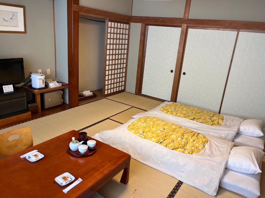 un salon avec deux lits et une table dans l'établissement Taiheikan, à Fujikawaguchiko