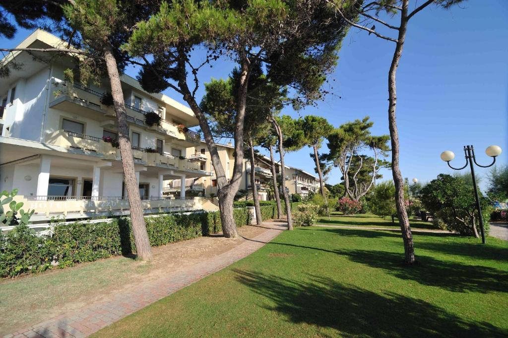un grand bâtiment blanc avec des arbres dans un parc dans l'établissement Hotel Abruzzo, à Pineto