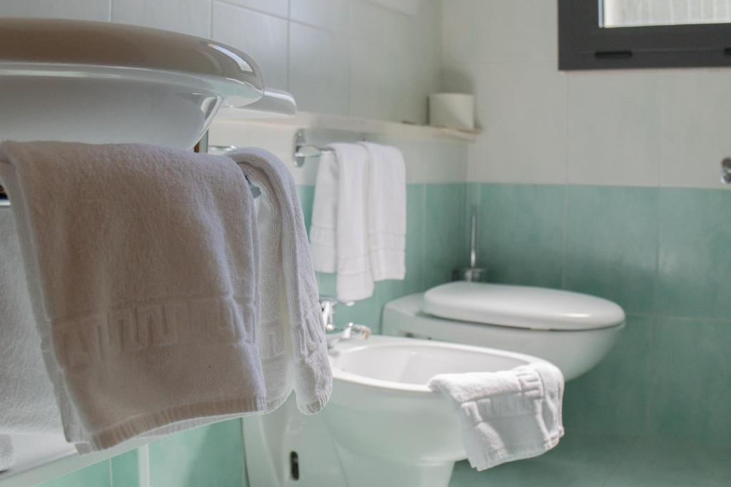La salle de bains est pourvue de toilettes, d'un lavabo et de serviettes. dans l'établissement Hotel Elvia, à Lignano Sabbiadoro