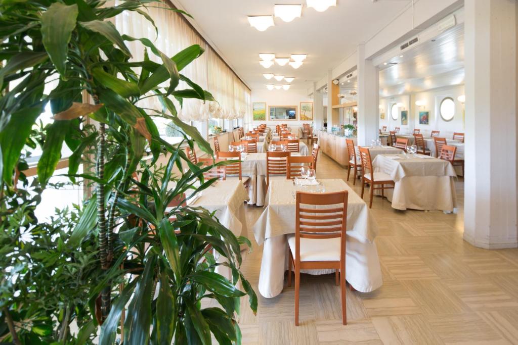 une salle à manger avec tables, chaises et plantes dans l'établissement Hotel Esplanade, à Marina di Pietrasanta