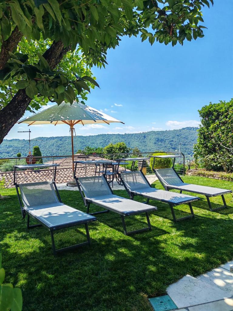 une rangée de chaises et un parasol dans l'herbe dans l'établissement Villa delle Agavi, à Costermano sul garda