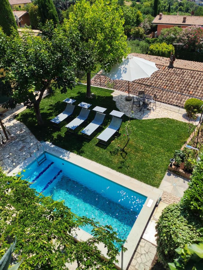 - une vue sur la piscine bordée de chaises longues et d'arbres dans l'établissement Villa delle Agavi, à Costermano sul garda