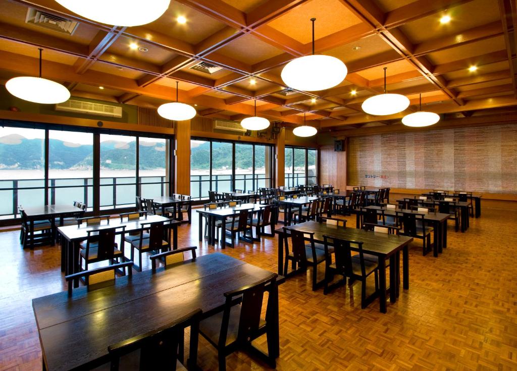 une salle à manger avec tables, chaises et fenêtres dans l'établissement Okukinosaki Seaside Hotel, à Toyooka