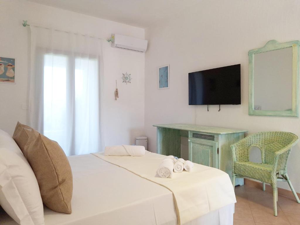 une chambre avec un lit, un bureau et une télévision dans l'établissement Neo Hotel Tre Monti, à Baja Sardinia