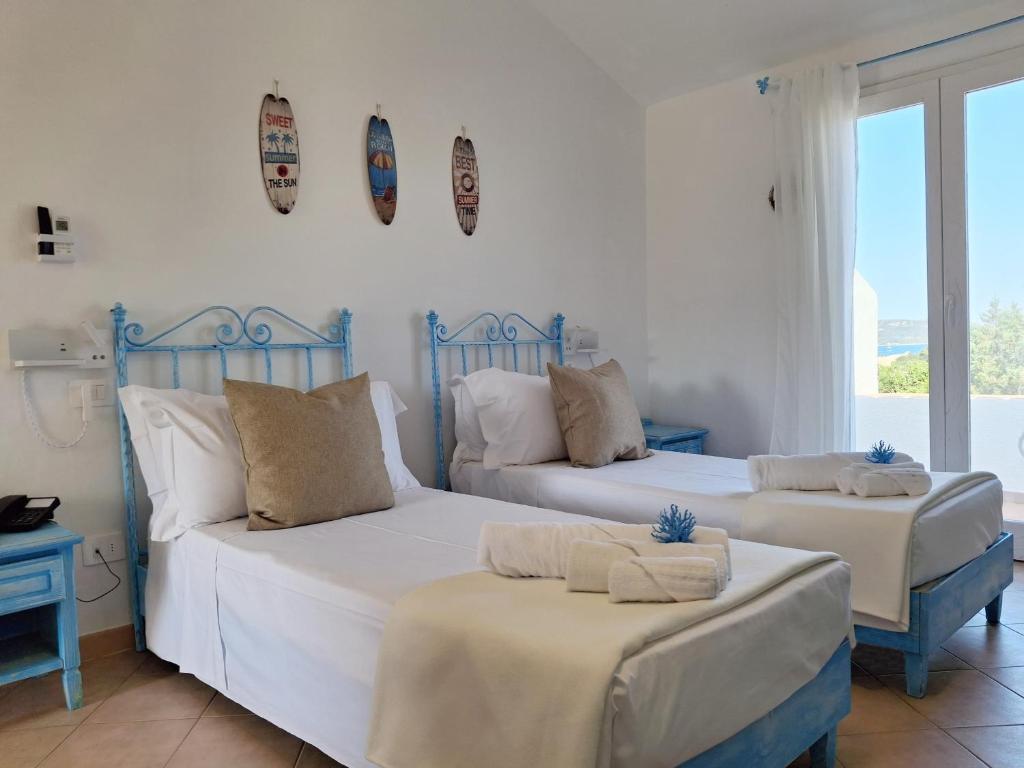 deux lits dans une chambre avec des murs et des fenêtres blancs dans l'établissement Neo Hotel Tre Monti, à Baja Sardinia