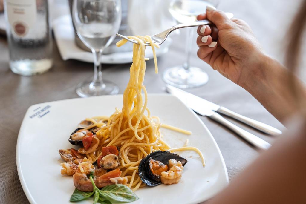 une personne mangeant des pâtes aux crevettes dans une assiette dans l'établissement Rouge Hotel International, à Milano Marittima