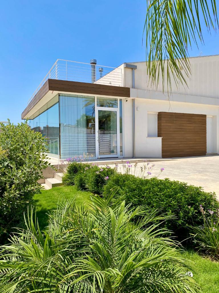 une maison moderne avec des fenêtres en verre et des buissons dans l'établissement Villa Lucia - Piscina Privata Riscaldata, à Marina di Ragusa