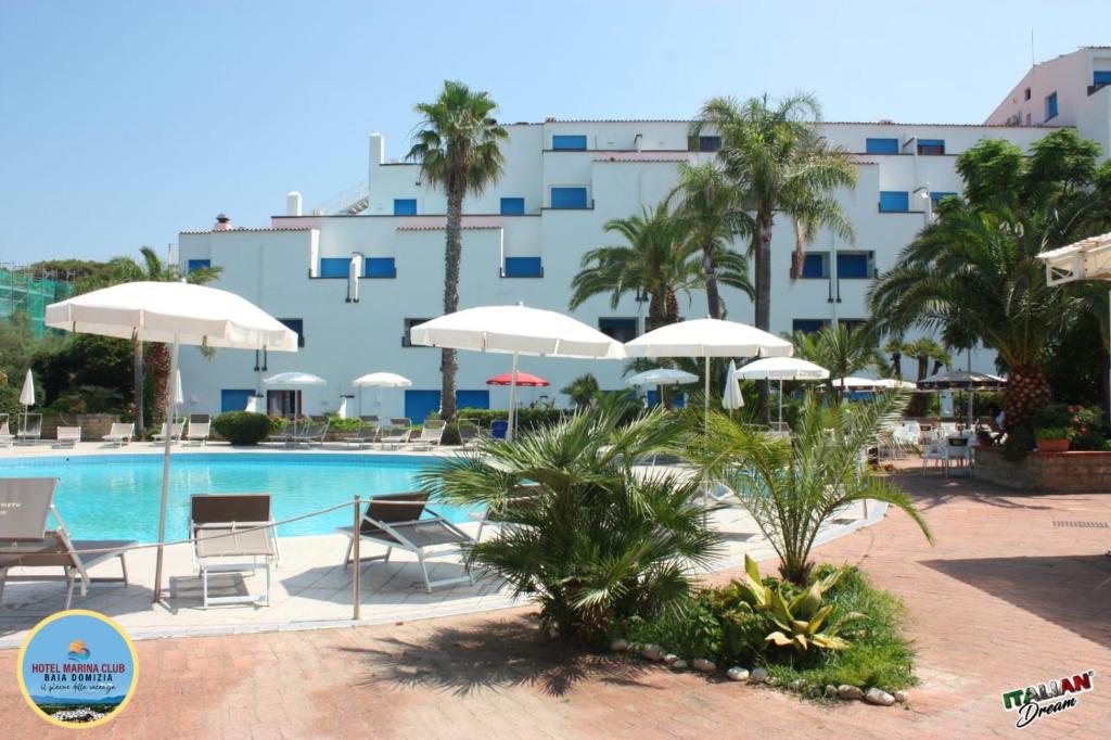 une piscine avec chaises et parasols devant un immeuble dans l'établissement Marina Club Hotel, à Baia Domizia