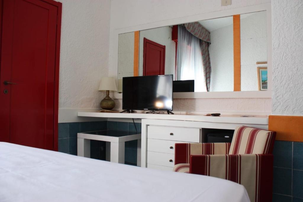 une chambre avec un lit, une télévision et un miroir dans l'établissement Marina Club Hotel, à Baia Domizia