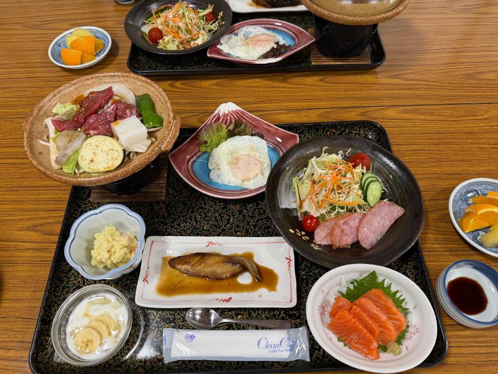 une table sur laquelle sont posées des assiettes de nourriture sur des plateaux dans l'établissement Akaishi Ryokan, à Fujikawaguchiko