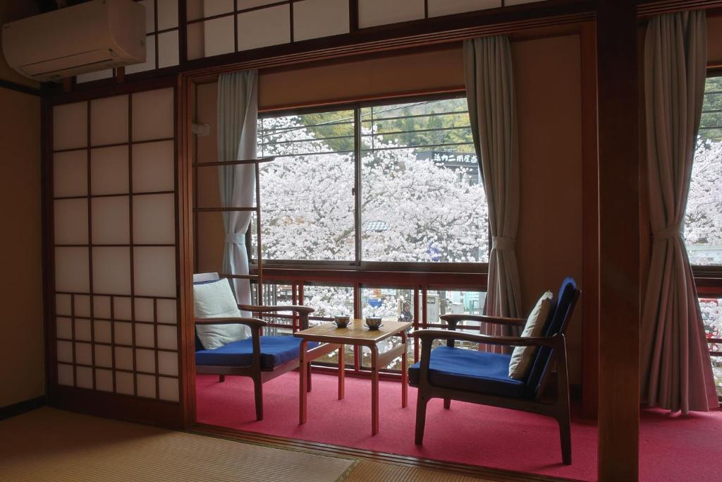 une pièce avec des chaises, une table et une fenêtre dans l'établissement Migumiya Ryokan, à Toyooka 5 autres photos