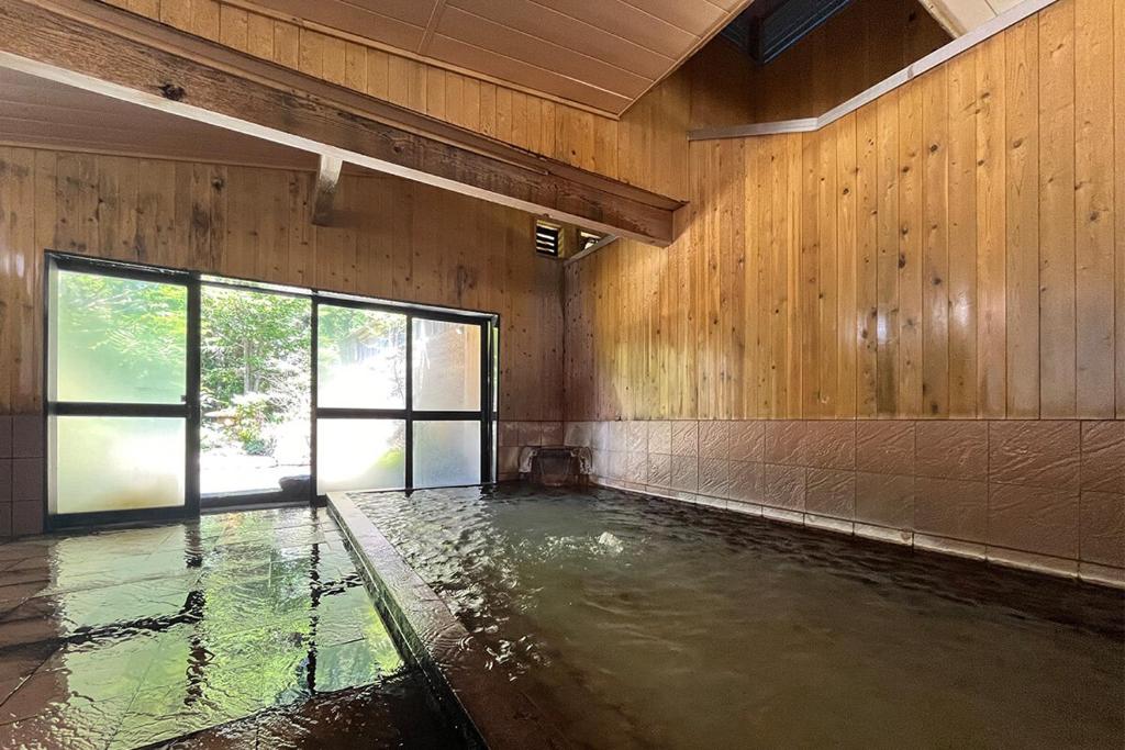 une piscine vide dans une pièce aux murs en bois dans l'établissement 湯の花ふわり 湯元館, à Hirayu