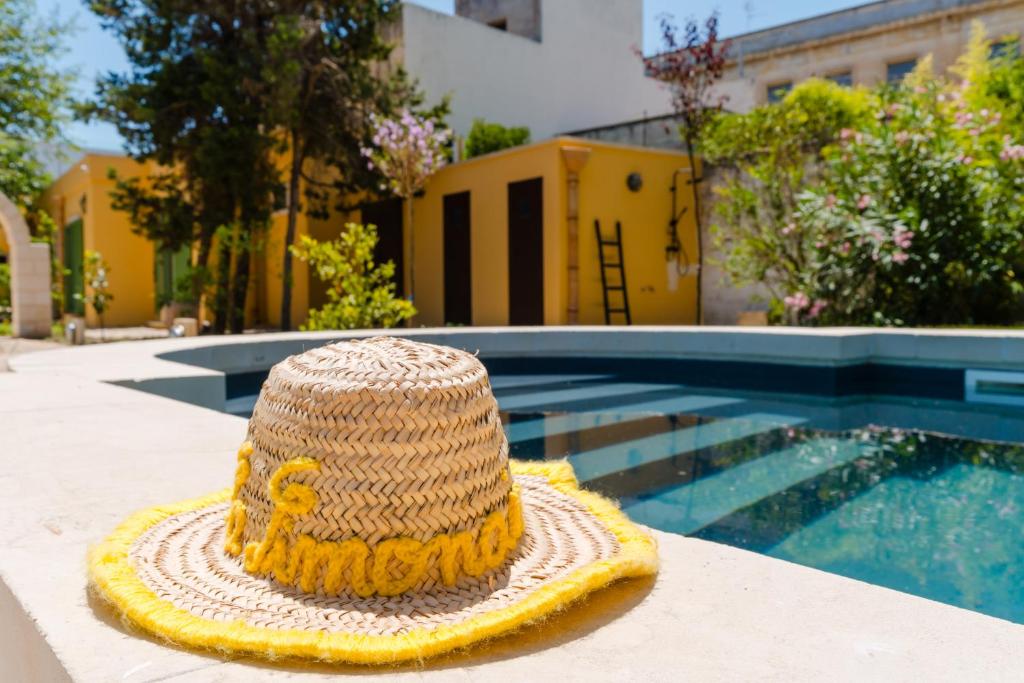 - un chapeau de paille assis sur une table à côté d'une piscine dans l'établissement La Limonaia Luxury Villa - Lecce Selection, à Lecce