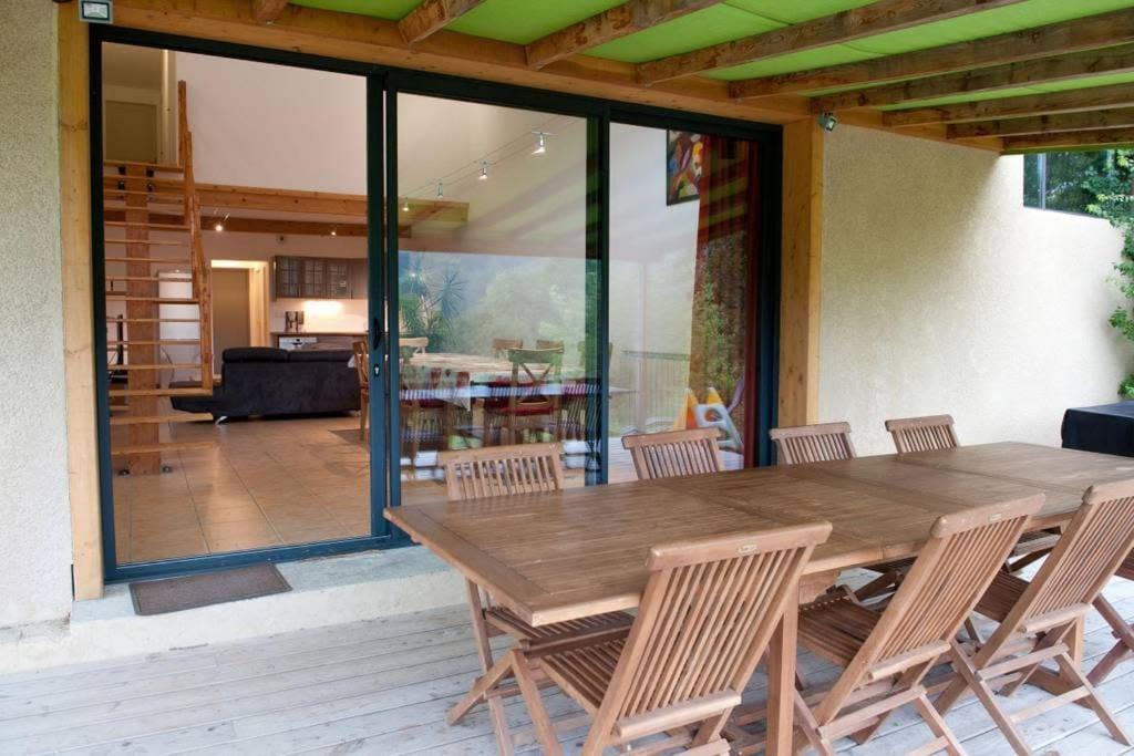 Une table à manger en bois et des chaises sont disponibles sur la terrasse. dans l'établissement Gites et Yourtes l'Aousière, à Entrepierres