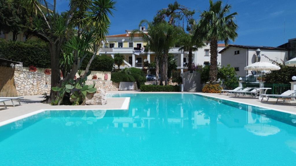 une grande piscine bleue devant une maison dans l'établissement Park Hotel Villa Americana, à Rodi Garganico