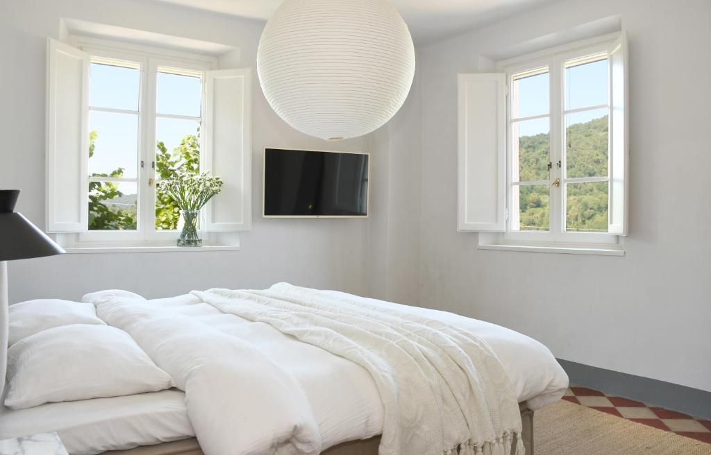 - une chambre blanche avec un grand lit et une télévision dans l'établissement Villa Mia Lucca - Modern Comfort in the Tuscan Hills, à Lucques