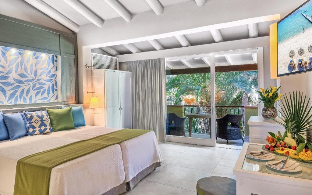 une chambre avec un lit et une table avec des fruits dessus dans l'établissement Forte Village Resort - Pineta, à Santa Margherita di Pula