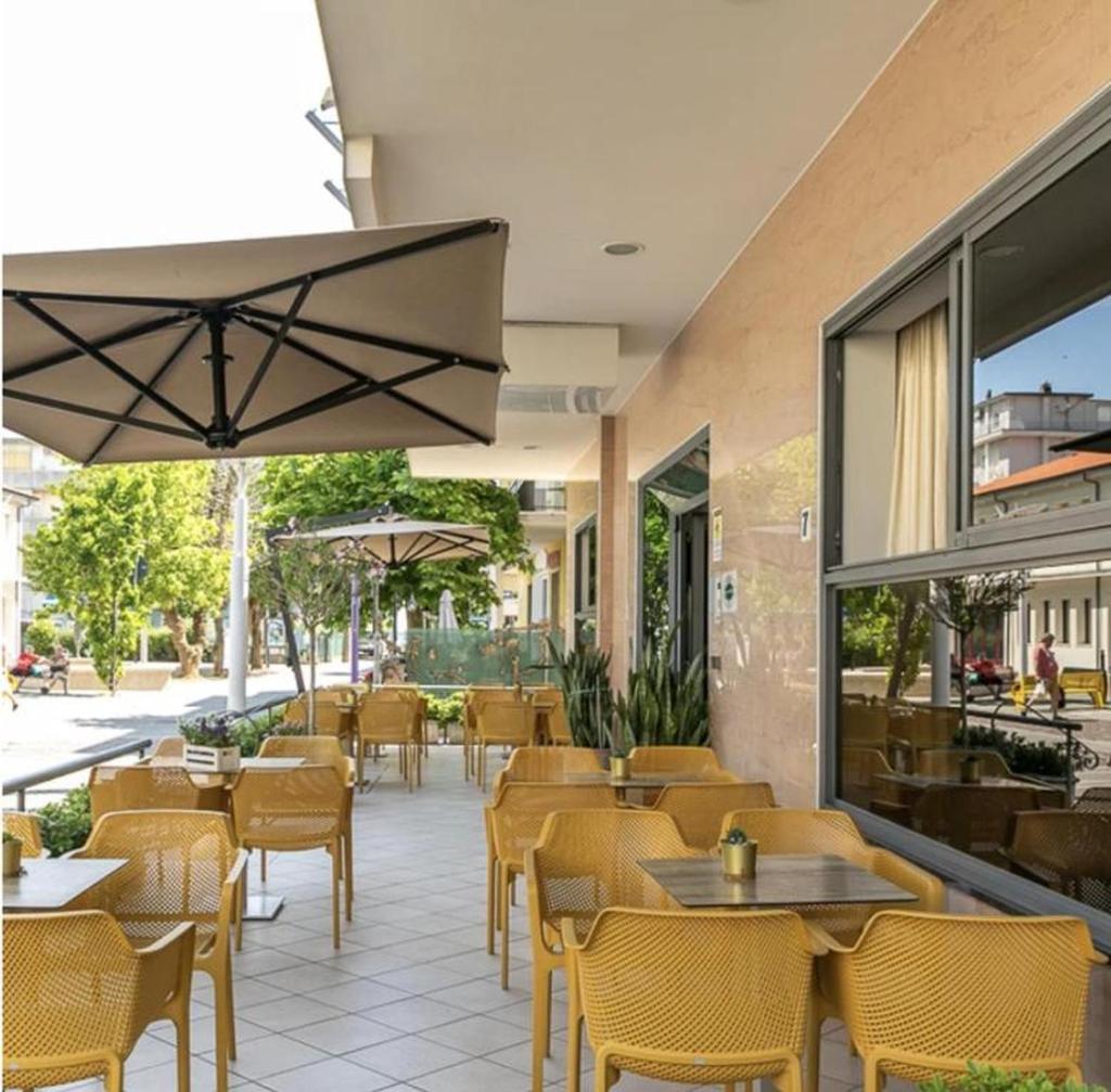 un restaurant avec des tables et des chaises et une terrasse dans l'établissement Hotel Atlantic, à Bellaria-Igea Marina