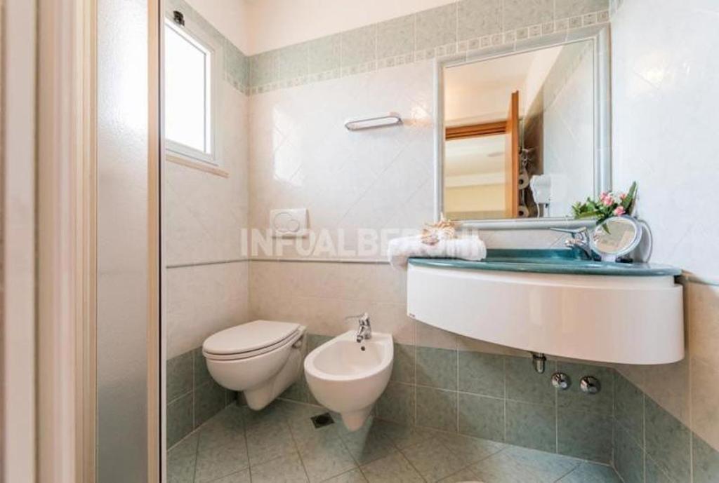 une salle de bain avec un lavabo, des toilettes et un miroir dans l'établissement Hotel Atlantic, à Bellaria-Igea Marina