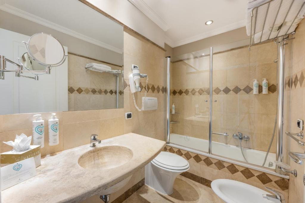 une salle de bain avec un lavabo, des toilettes et une douche dans l'établissement Tombolo Talasso Resort, à Marina di Castagneto Carducci