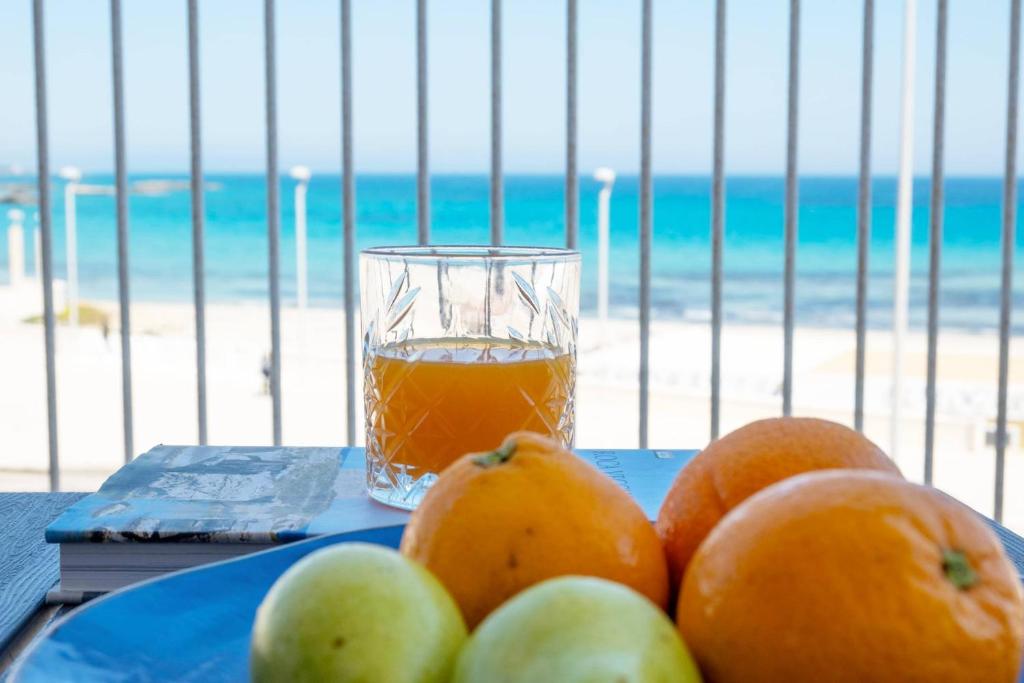 - un verre de jus d'orange assis sur une table à côté de la plage dans l'établissement Hotel Da Romano, à San Foca