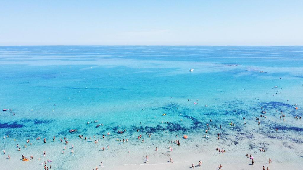 un groupe de personnes sur une plage près de l'eau dans l'établissement Hotel Da Romano, à San Foca