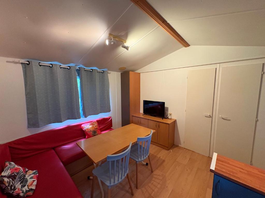 un salon avec un canapé rouge et une table dans l'établissement Manoir le Mingreaud-Bungalows, à Sainte-Gemme-la-Plaine