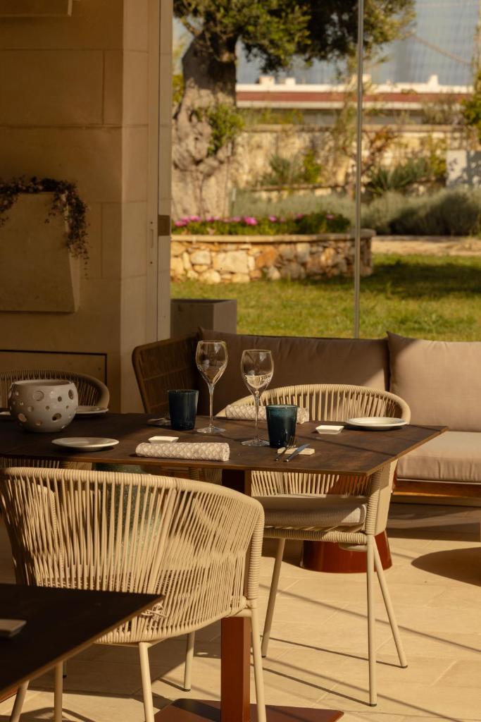 une table en bois avec deux chaises et une table avec des verres à vin dans l'établissement Metamare, à Cozze
