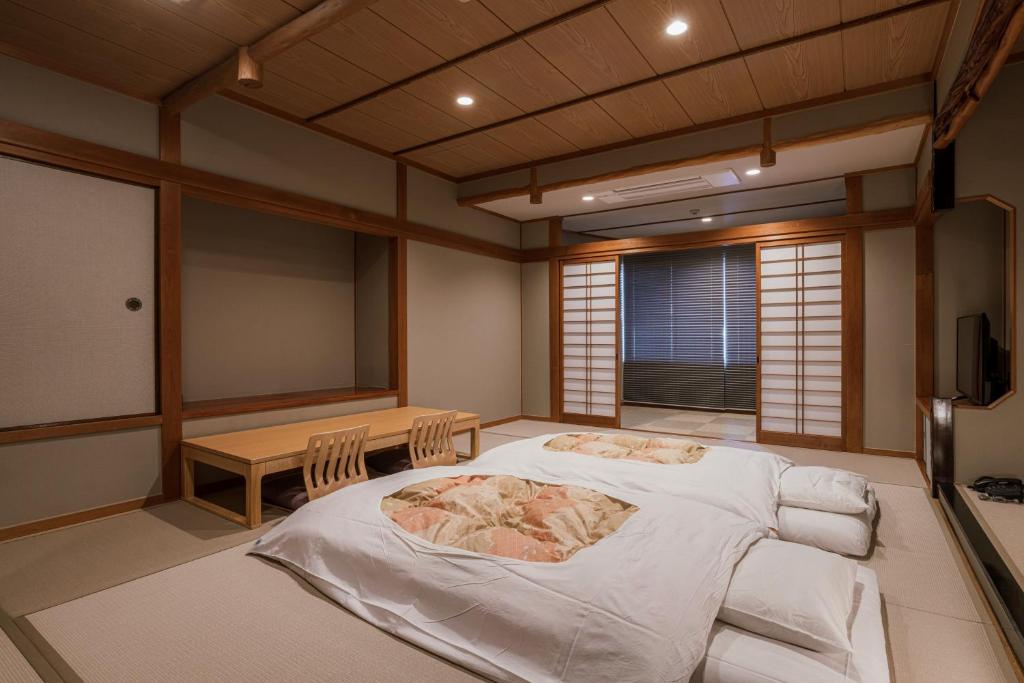 une pièce avec un lit et une table dedans dans l'établissement Shinzan Kinosaki, à Toyooka