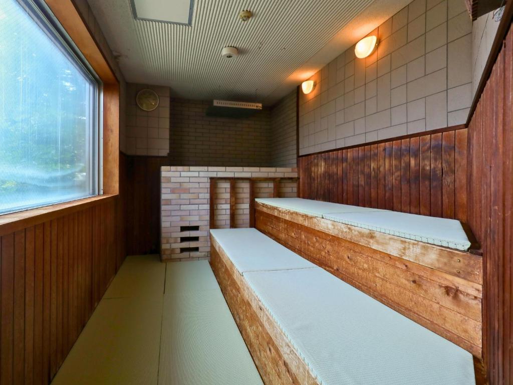 un sauna avec des sièges en bois et une fenêtre dans l'établissement Ikoi no mura Notohanto, à Shika
