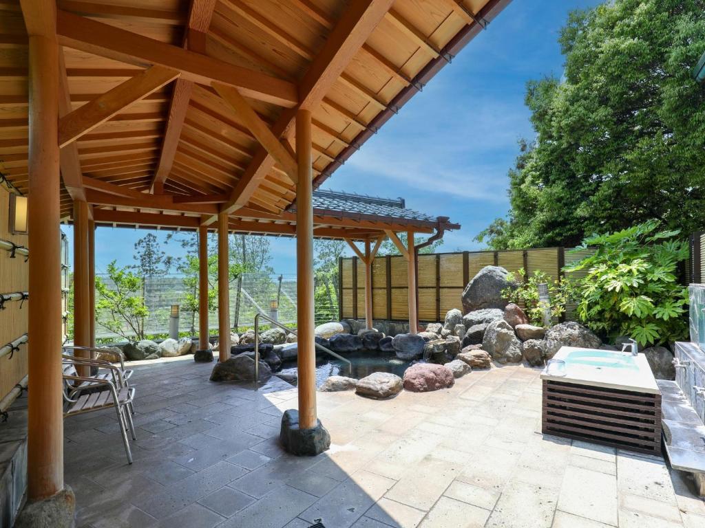 un patio avec une pergola en bois et un étang dans l'établissement Ikoi no mura Notohanto, à Shika