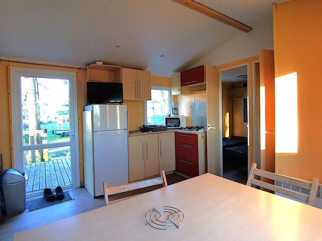 une cuisine avec une table et un réfrigérateur dans l'établissement MH First 6pers 30min PuyduFou HellFest, à La Boissière-de-Montaigu