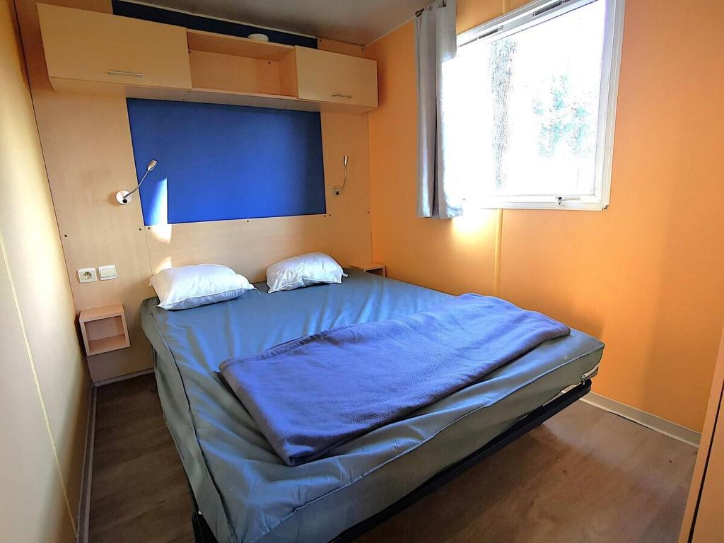 une chambre avec un lit avec des draps bleus et une fenêtre dans l'établissement MH First 6pers 30min PuyduFou HellFest, à La Boissière-de-Montaigu