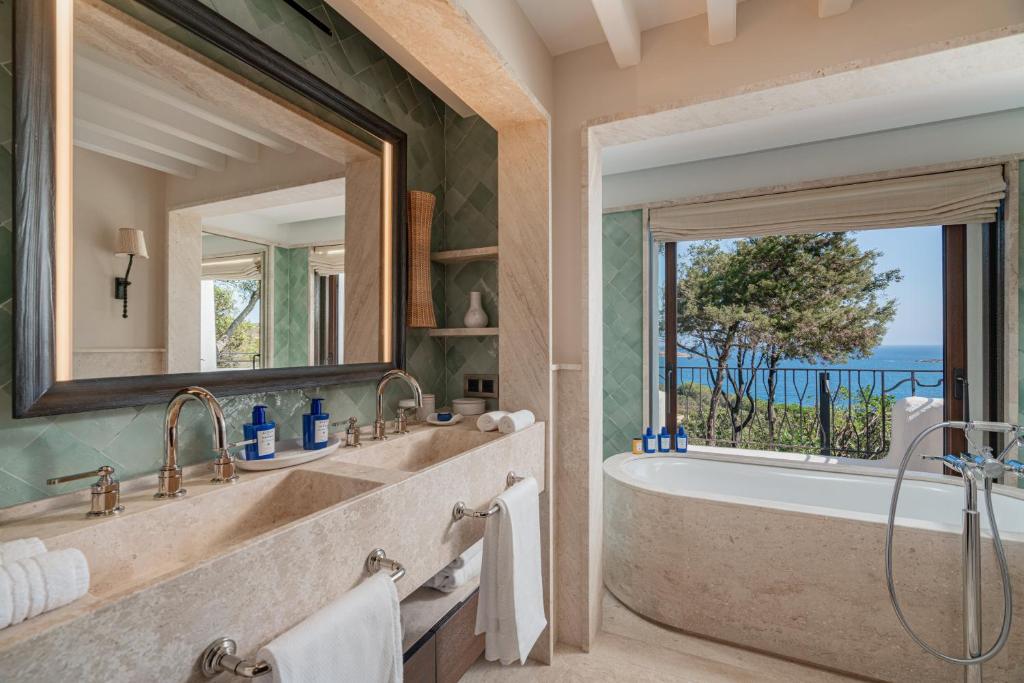 une salle de bain avec baignoire et une grande fenêtre dans l'établissement Hotel Pitrizza, Costa Smeralda, à Porto Cervo