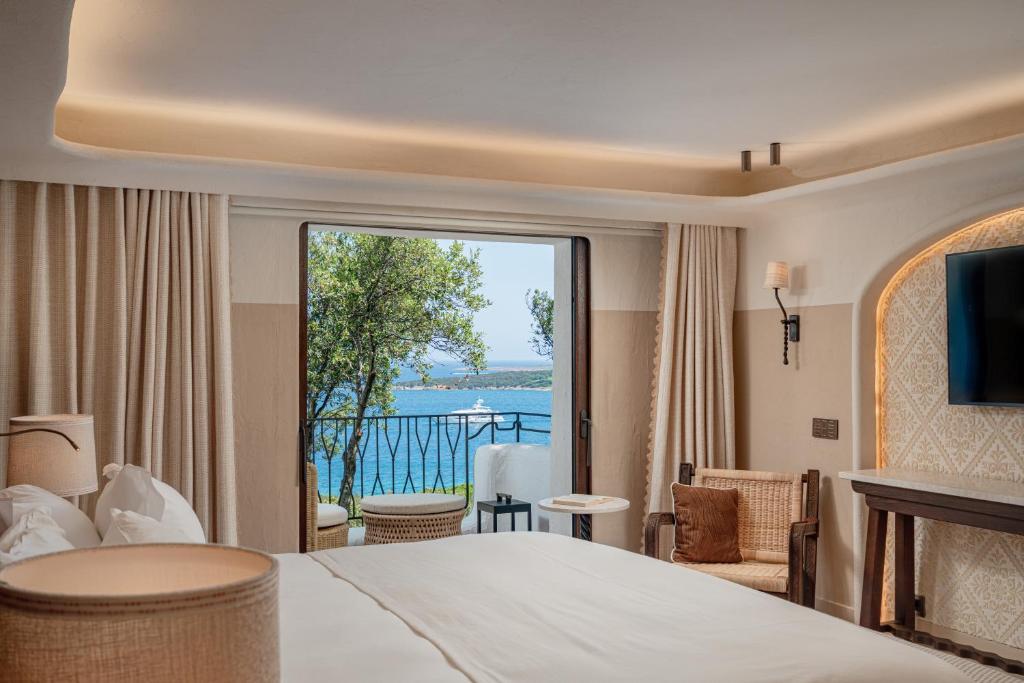 une chambre d'hôtel avec un grand lit et un balcon dans l'établissement Hotel Pitrizza, Costa Smeralda, à Porto Cervo