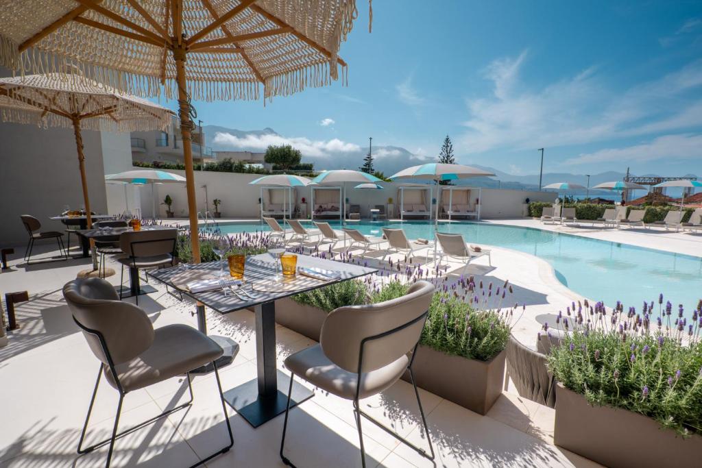 un patio avec une table et des chaises à côté d'une piscine dans l'établissement Resort La Battigia Beach & Spa, à Alcamo Marina
