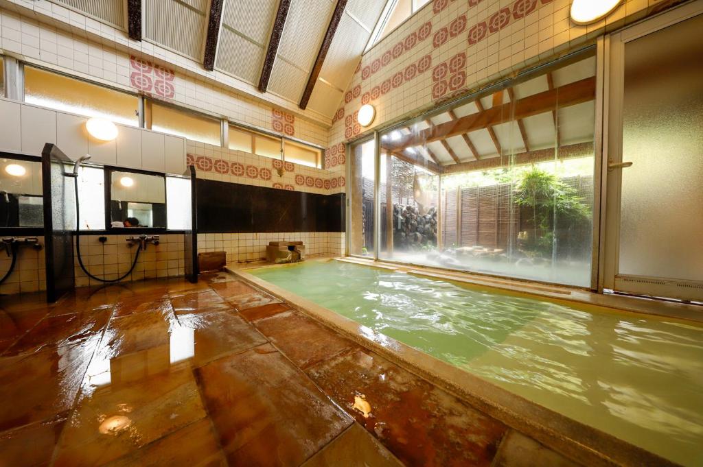 une piscine intérieure dans une grande pièce avec une grande fenêtre dans l'établissement Ryokan Kiritani Hakoneso, à Hakone