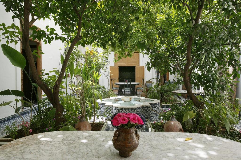 une table avec un vase avec des fleurs roses dans l'établissement Riad Lune et Soleil, à Fès 15 autres photos