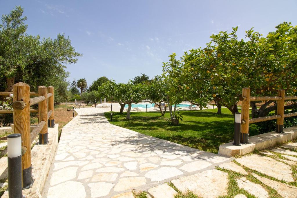 un chemin avec des arbres et une clôture en bois dans l'établissement Casale la Macina Residence Scopello, à Scopello