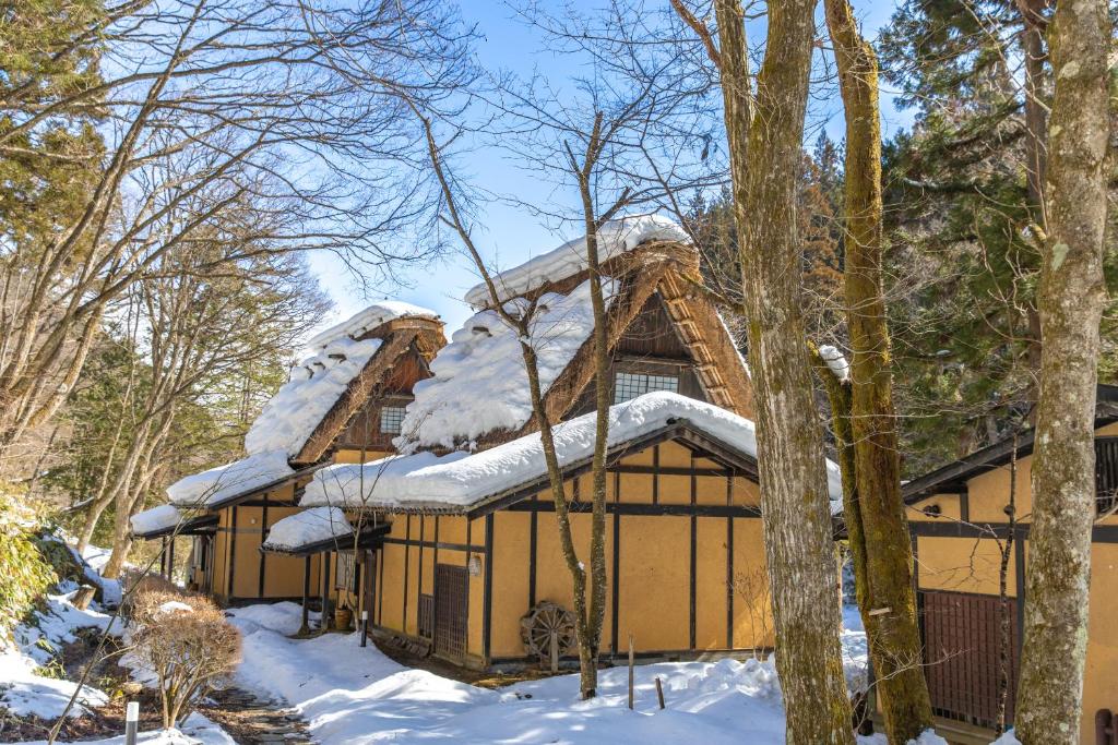 une cabane dans les bois avec de la neige sur le toit dans l'établissement Wanosato, à Takayama
