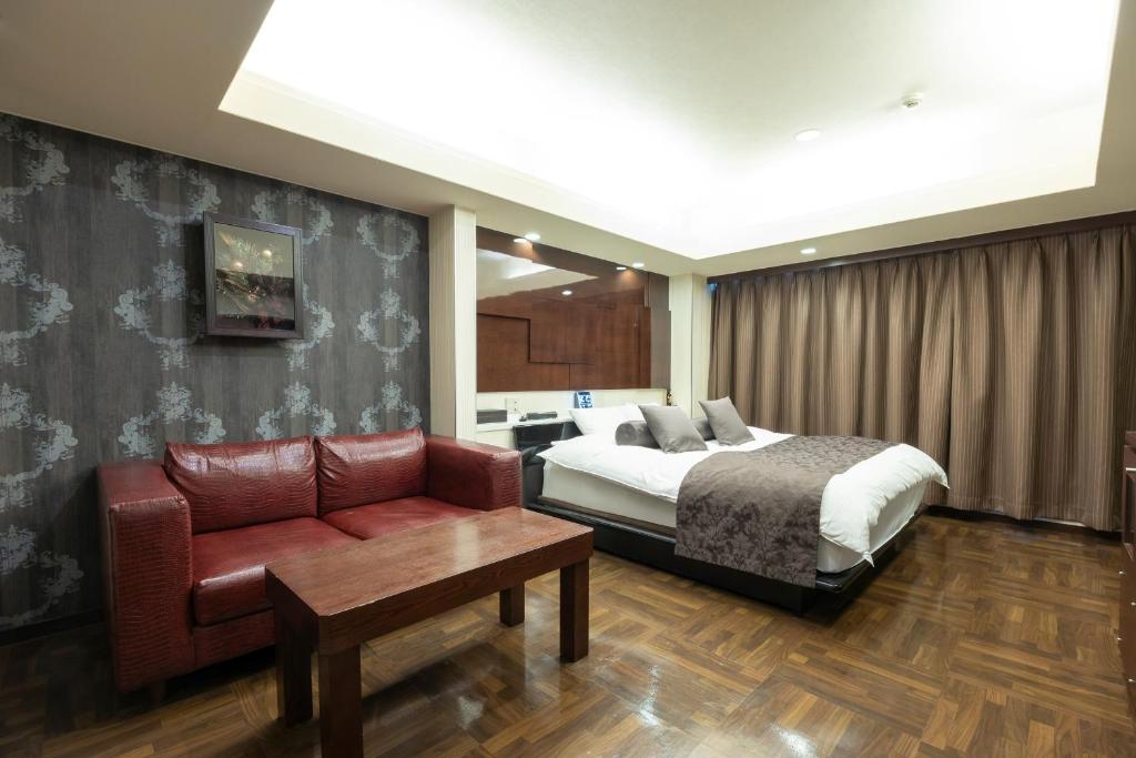 une chambre d'hôtel avec un lit et un canapé dans l'établissement ホテル アン 岐阜-大人専用, à Gifu