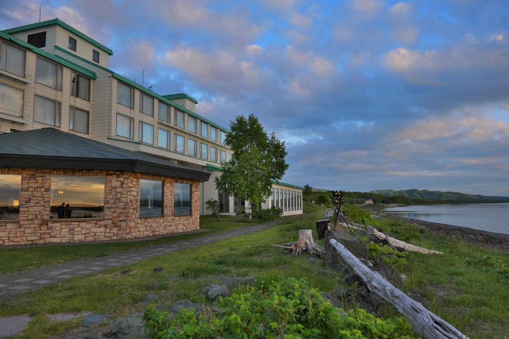 un bâtiment situé sur une colline à côté d'une masse d'eau dans l'établissement Lake Saroma Tsuruga Resort, à Kitami