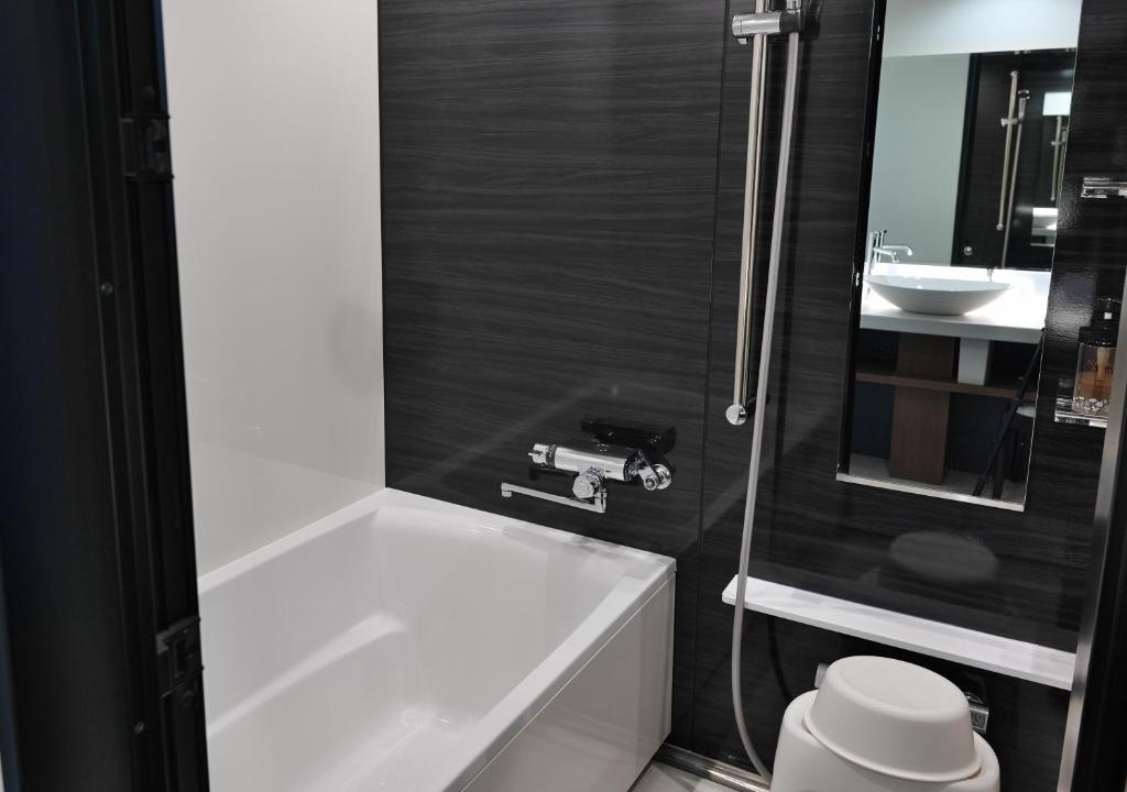 une salle de bain avec une baignoire blanche et un lavabo dans l'établissement Lake Saroma Tsuruga Resort, à Kitami