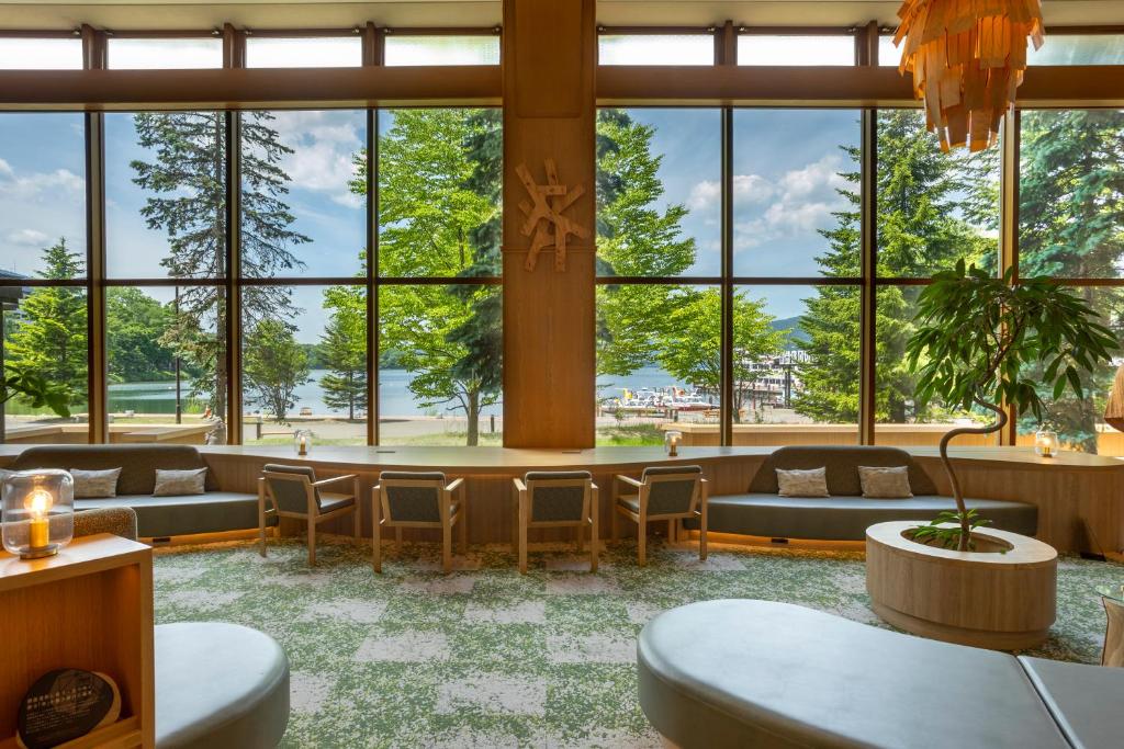 - un hall avec de grandes fenêtres, des canapés et des tables dans l'établissement THE FOREST AKAN Tsuruga Resort, à Akankohan
