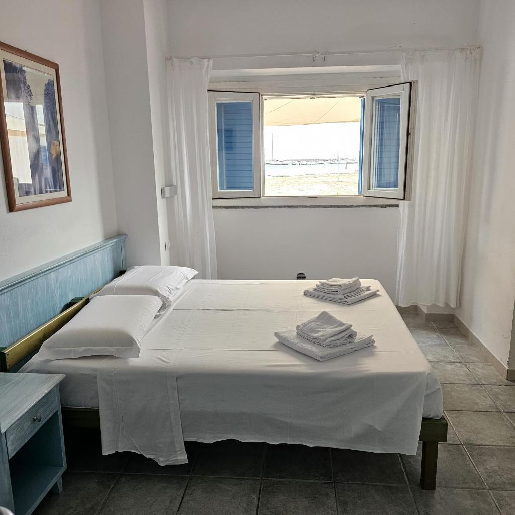 deux lits dans une chambre blanche avec une fenêtre dans l'établissement Vel Marì - Rooms on the Beach, à Alghero