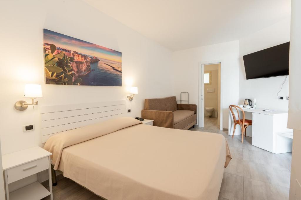 une chambre avec un grand lit blanc et un bureau dans l'établissement Garden Hotel Ripa, à Vieste