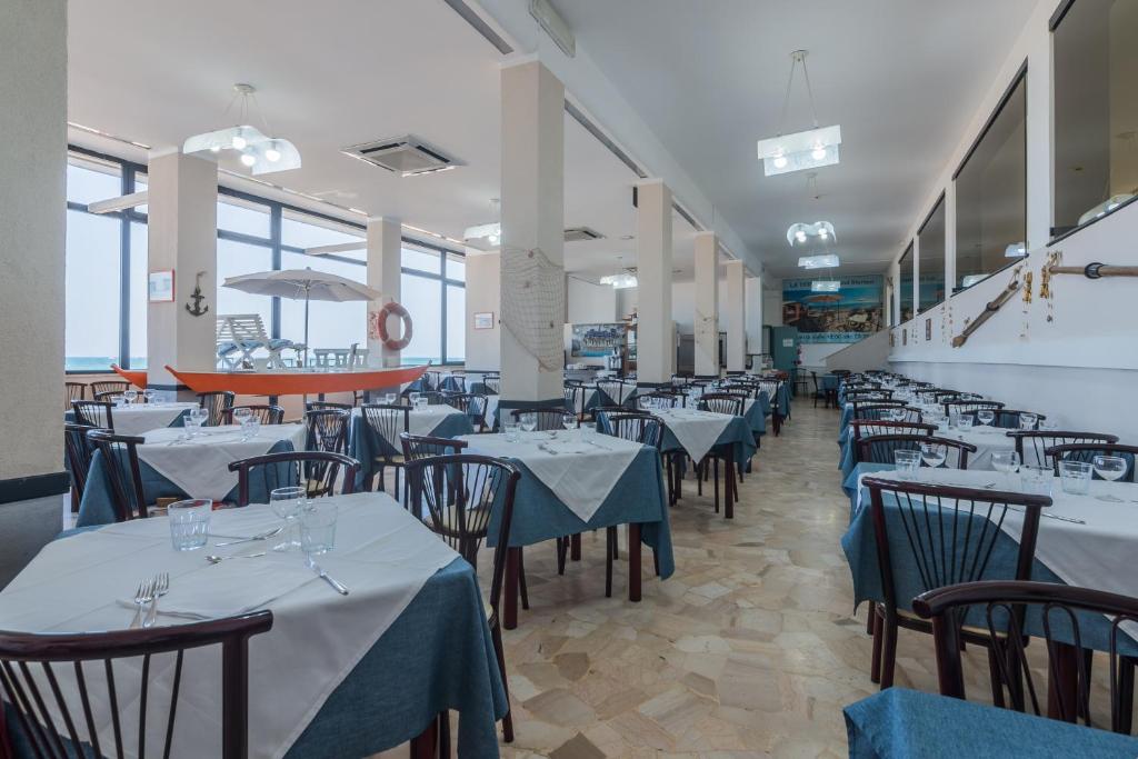 une salle à manger avec tables et chaises et nappes bleues dans l'établissement Hotel Blumen, à Rimini
