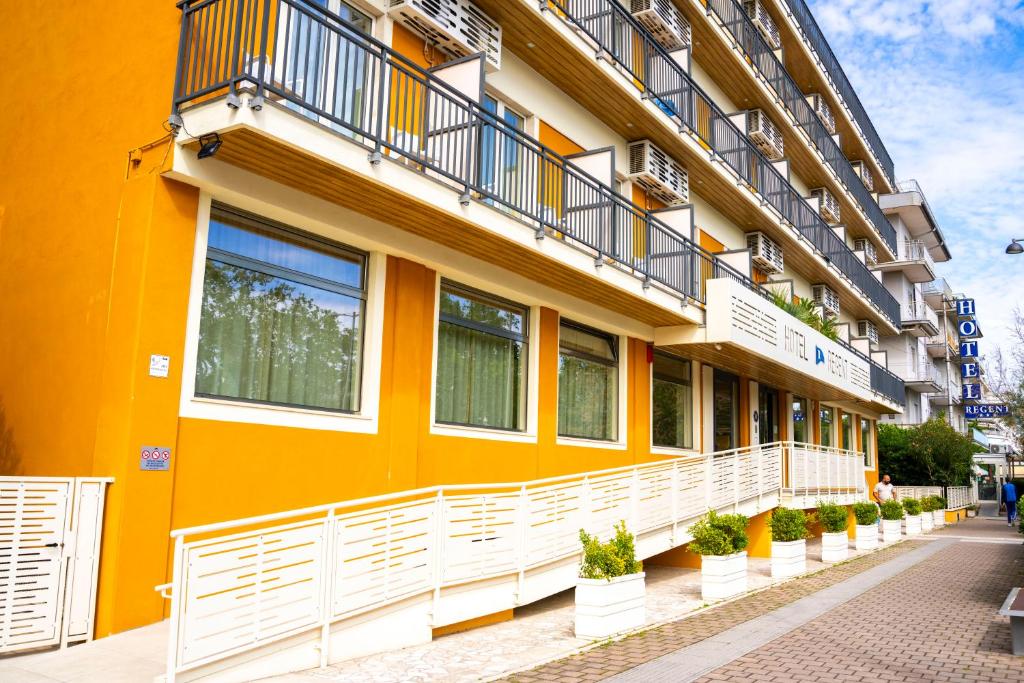 un bâtiment jaune avec un balcon et des plantes en pot dans l'établissement Hotel Regent, à Pescara