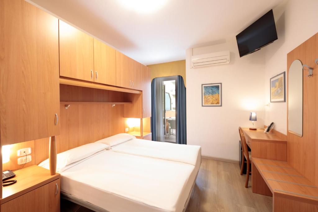 une chambre avec un grand lit blanc et un bureau dans l'établissement Hotel Garni Losanna, à Bibione